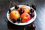Fresh apricot and cherry in a bowl on wooden table