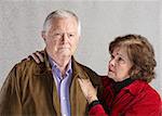 Concerned senior husband and wife over gray background