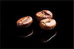 Three coffee beans isolated on black background.