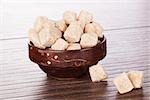 Brown sugar cubes in wooden bowl on brown background. Natural sugar concept.