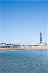 View across the sea of the waterfront and beach with the Blackpool Tower and piers, Blackpool, England