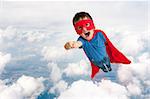 superhero boy child flying upwards through the clouds