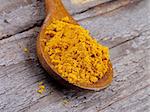 Curry Powder in Wooden Spoon closeup on Rustic Wooden background