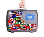 Used plastic suitcase with lots of small stickers, large sticker of the United Nations