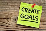 create goals reminder - handwriting on a green sticky note against grained and knotted wood board