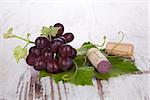 Red wine grape with wine cork on white wooden textured background. Culinary luxurious wine drinking.