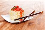 Rice with sweet and sour sauce with chopsticks on wooden background. Culinary traditional eating.