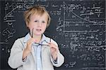 Cute pupil holding glasses against math and science doodles