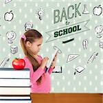 Cute girl using tablet against red apple on pile of books