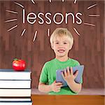 The word lessons and cute boy using tablet against red apple on pile of books