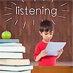 The word listening and cute boy using tablet against red apple on pile of books