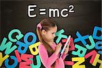 Cute girl using tablet against alphabet magnets in a jumble on blackboard