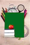 Red apple on pile of books against students desk with green page