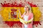 Young pretty student pointing and reading against spain flag in grunge effect