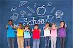 Elementary pupils smiling showing thumbs up against blue chalkboard