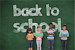 Elementary pupils reading against green chalkboard with back to school message