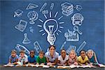 Cute pupils smiling at camera with teacher against blue chalkboard