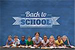 Cute pupils smiling at camera with teacher against blue chalkboard with back to school message