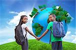 Cute pupils holding hands against green hill under blue sky with globe