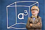 Cute pupil dressed up as teacher  against blue chalkboard with a cubed