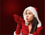 Pretty brunette in santa outfit blowing over hands on red vignette background