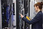 Technician using digital cable analyzer on server  in large data center