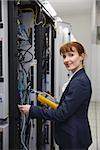 Happy technician using digital cable analyzer on server  in large data center