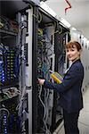 Happy technician using digital cable analyzer on server  in large data center