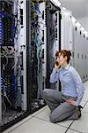 Technician talking on phone while analysing server in large data center