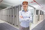 Serious data technician looking at camera  in large data center