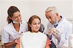 Dentist and assistant smiling with patient in chair at the dental clinic