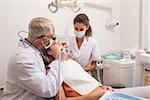 Dentist and assistant examining patients teeth at the dental clinic