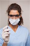 Dentist in surgical mask and scrubs holding tool at the dental clinic