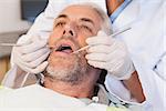 Dentist examining a patients teeth in the dentists chair at the dental clinic