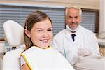 Pediatric dentist and little girl smiling at camera at the dental clinic