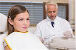 Pediatric dentist and little girl sitting in chair at the dental clinic