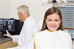 Smiling little girl looking at camera in dentists chair at the dental clinic