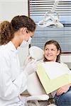 Pediatric dentist speaking with little girl in the dentists chair at the dental clinic