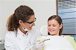 Pediatric dentist smiling with little girl in the chair at the dental clinic