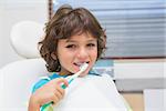 Little boy in dentists chair using toothrbrush at the dental clinic