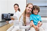 Pediatric dentist smiling at camera with little boy and his mother at the dental clinic