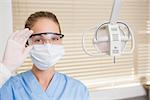 Dentist in surgical mask and protective glasses looking at camera at the dental clinic