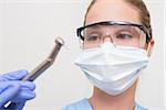 Dentist in surgical mask and protective glasses holding drill at the dental clinic