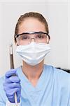 Dentist in blue scrubs holding dental drill at the dental clinic