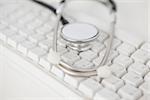 Stethoscope lying on white keyboard on white desk