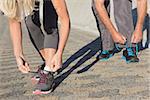 Couple tying their laces of running shoes on a sunny day