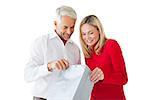 Smiling couple looking into shopping bag on white background
