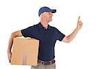 Happy delivery man holding cardboard box and pointing up on white background