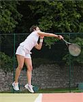 Pretty tennis player jumping and hitting on a sunny day