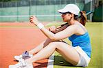 Pretty tennis player sitting on court on a sunny day